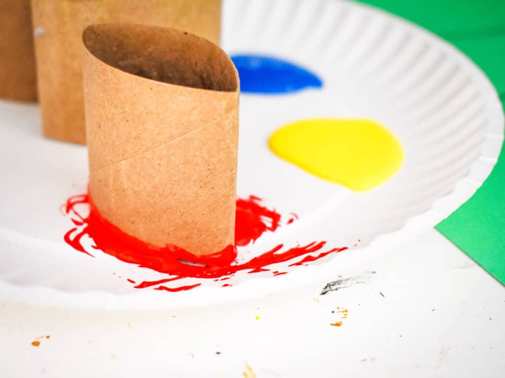 Dipping toilet paper roll into red paint