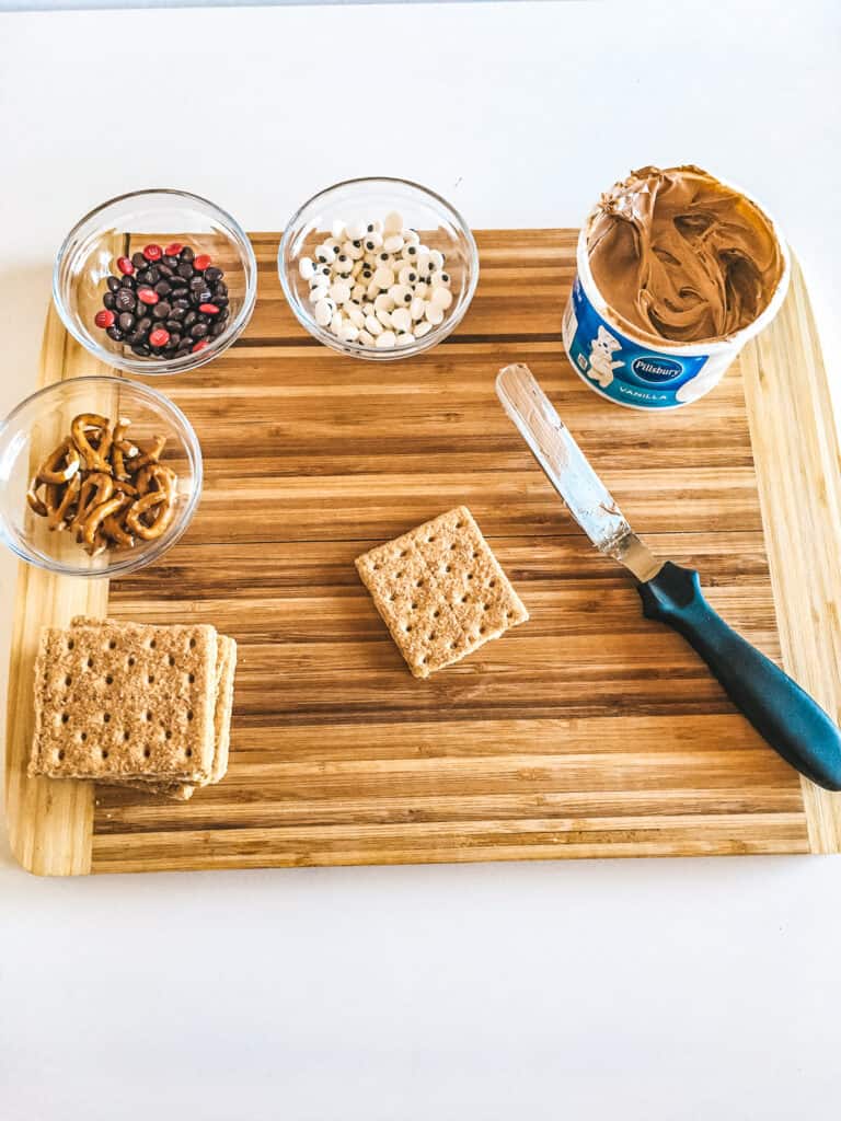 Wooden cutting board with supplies to make reindeer graham cracker treats