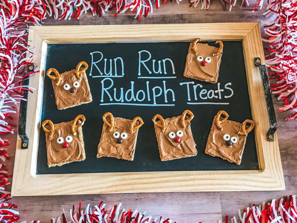 Chalk board with run run rudolph wrote on it and decorated graham crackers