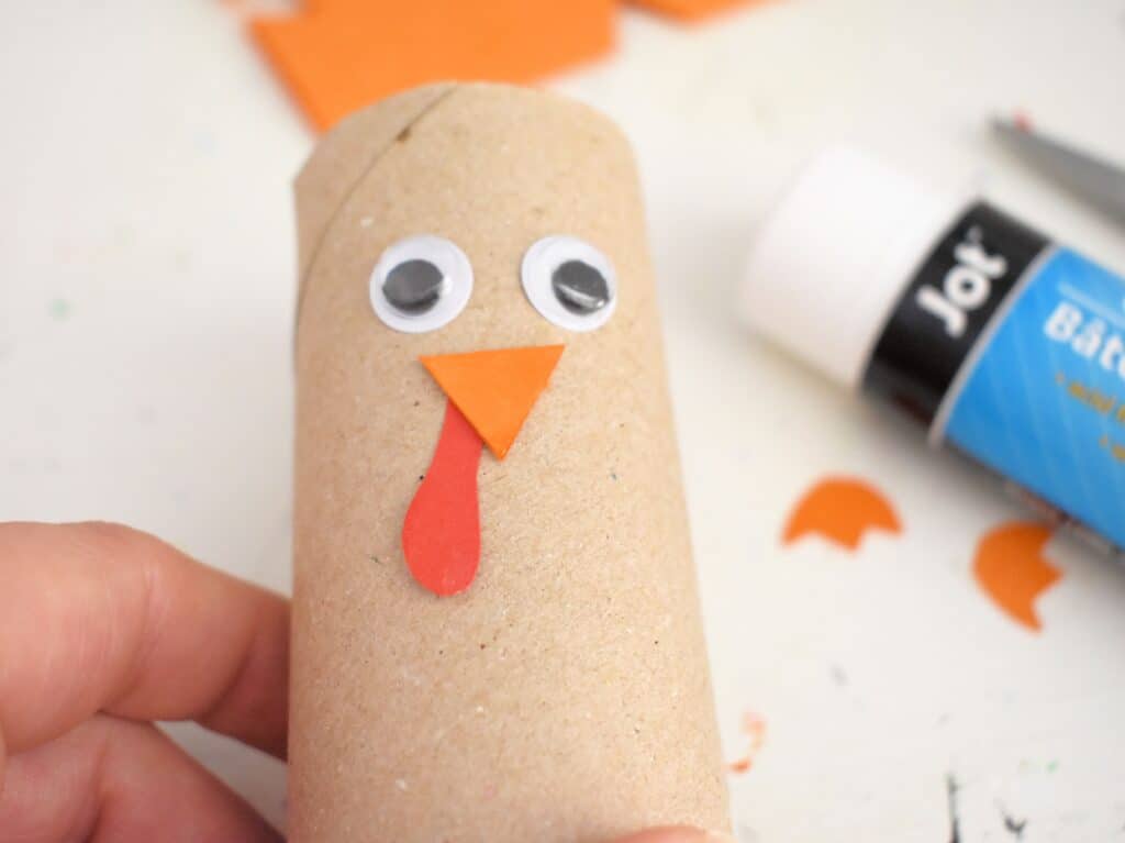 Googly eyes, nose and snood glued on toilet paper roll