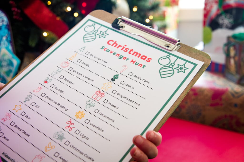 Child holding Christmas Scavenger Hunt on a clipboard