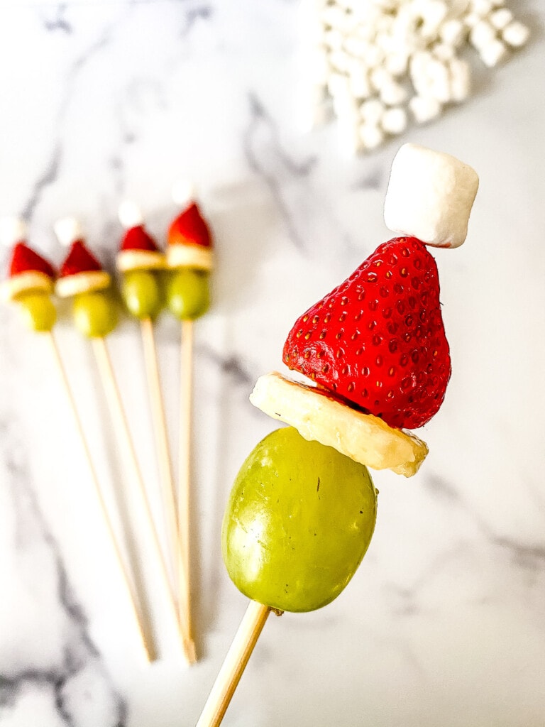 Skewer with grape, banana, strawberry and miniature marshmallow to make Grinch Kabobs
