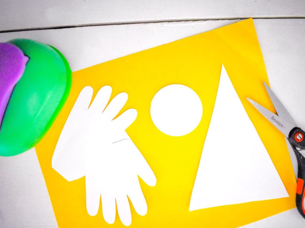 Yellow paper with handprints and angle pieces cut out of white paper