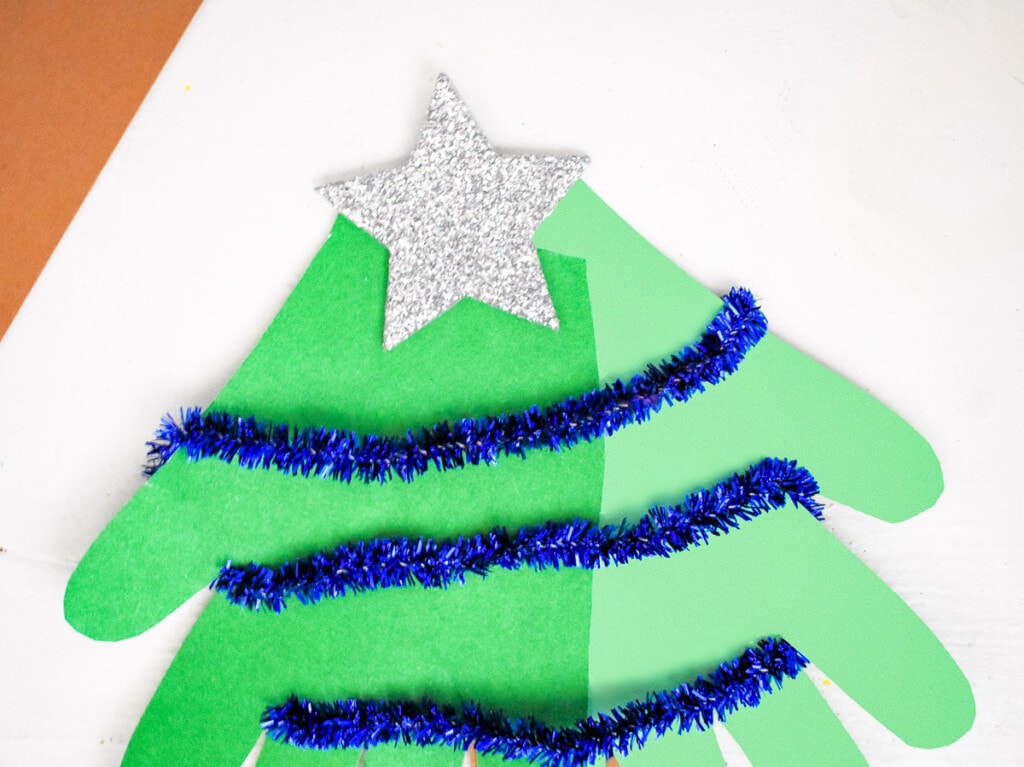 Handprint Christmas Tree decorated with blue pipe cleaner and silver star on top