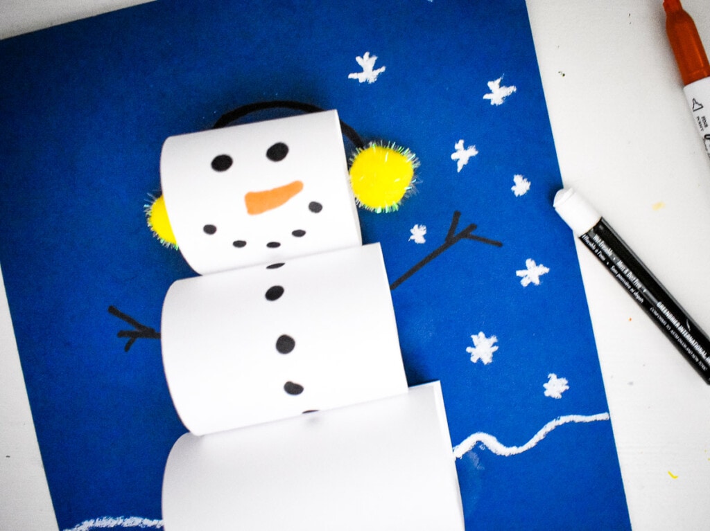 Drawing hands and snowflakes on blue paper for snowman