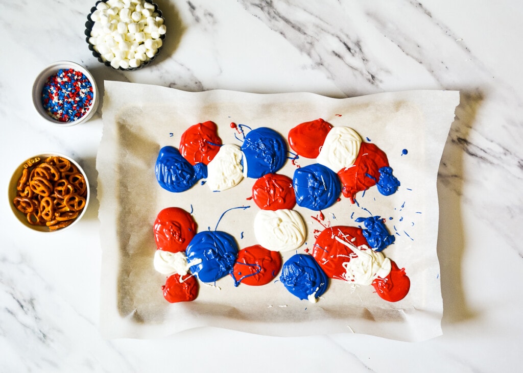 Drops of red, white and blue candy melts on wax paper.