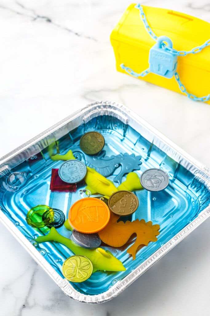 Square Aluminum Foil pan with blue water and plastic toys.