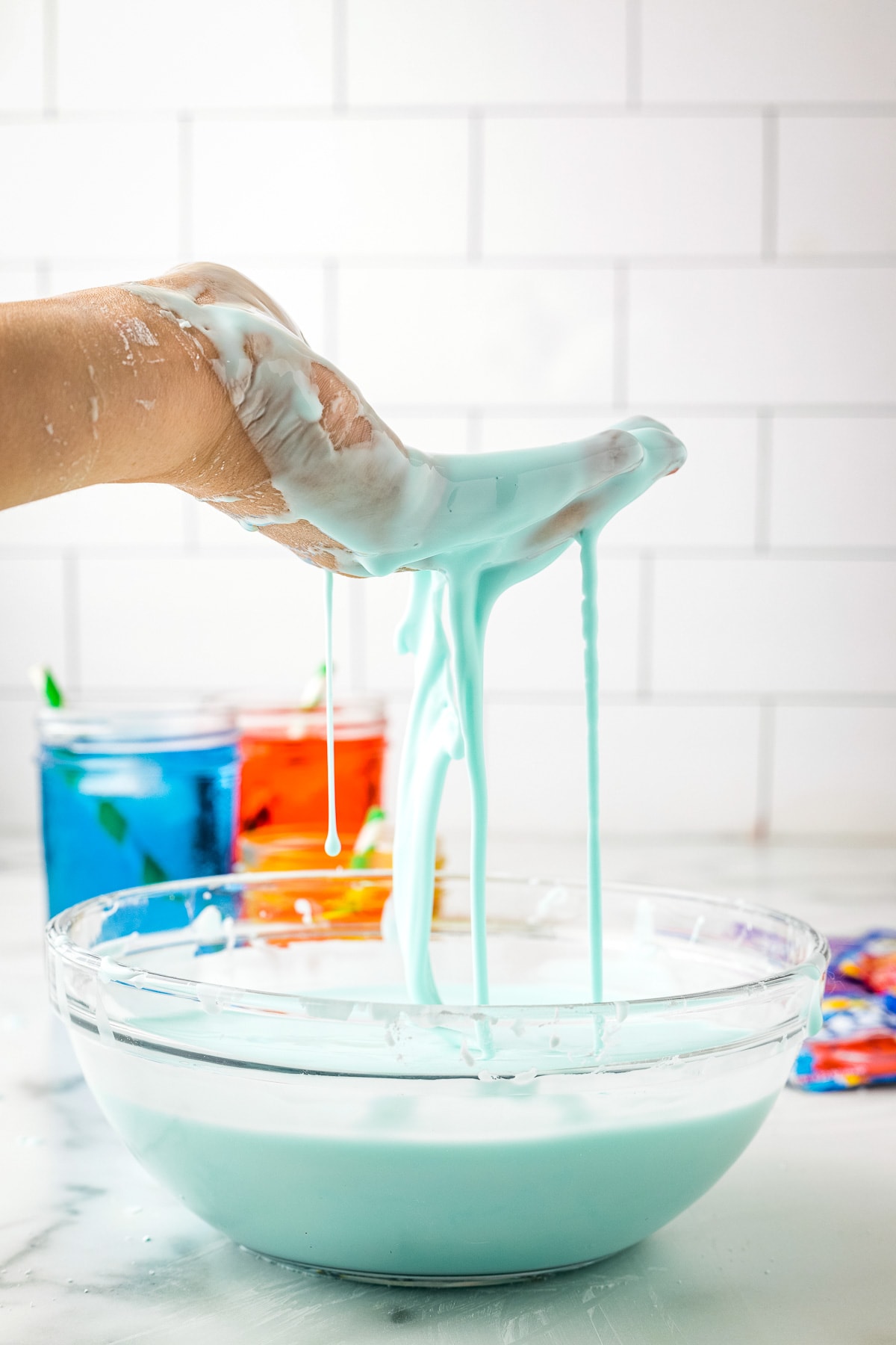 Hand with Kool-Aid Oobleck in it above bowl