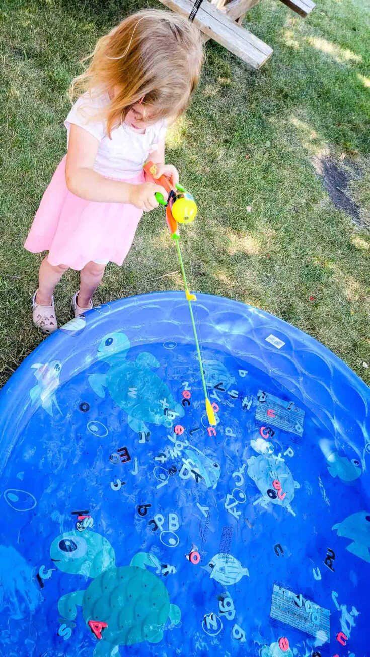 Little girl fishing for letters in kiddie pool