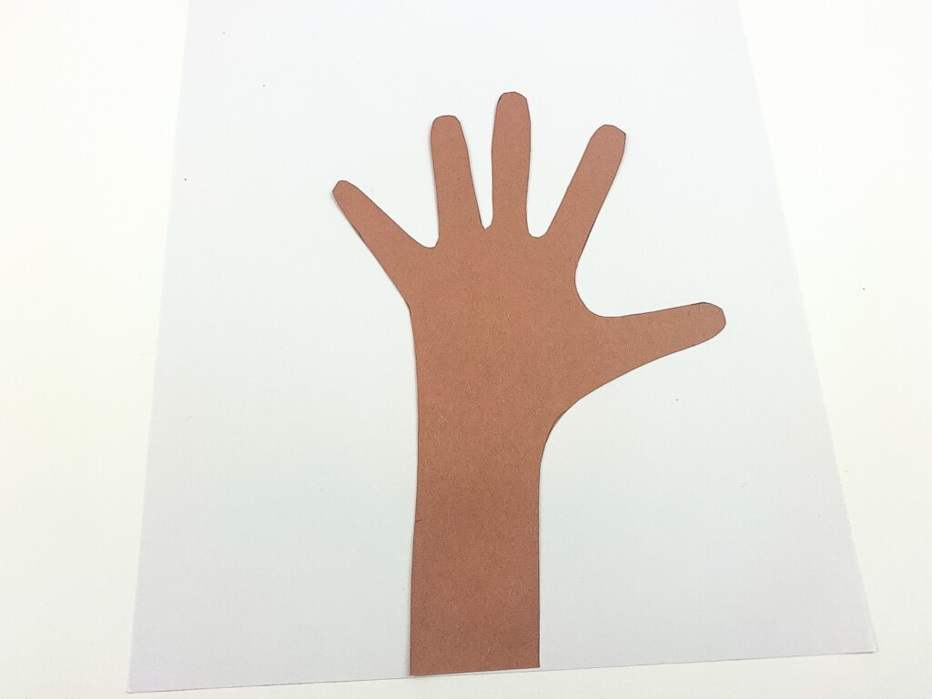 Brown construction paper cut out of hand and arm pasted on white background