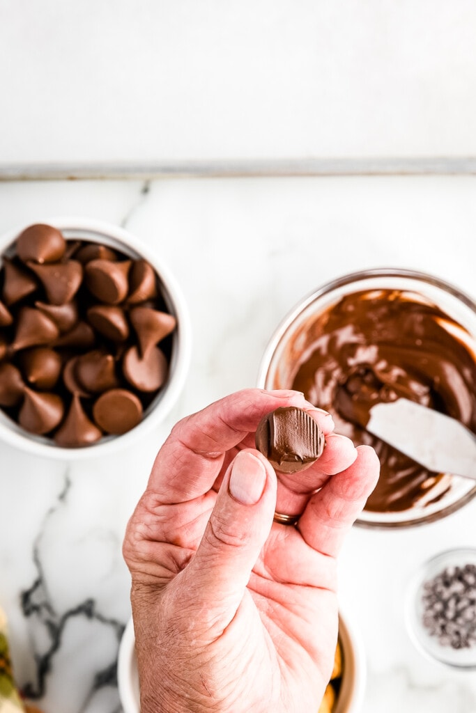 Spreading melted chocolate on the flat pieces of a Hershey Kiss