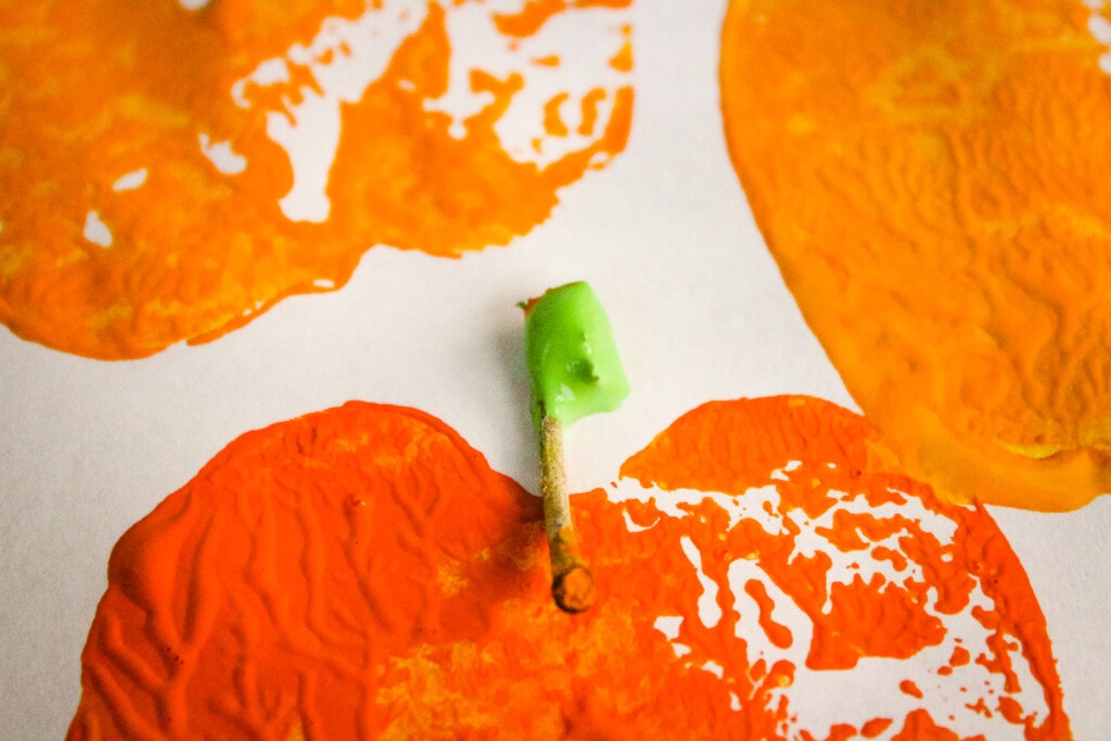 Apple stem dipped in green paint on white paper