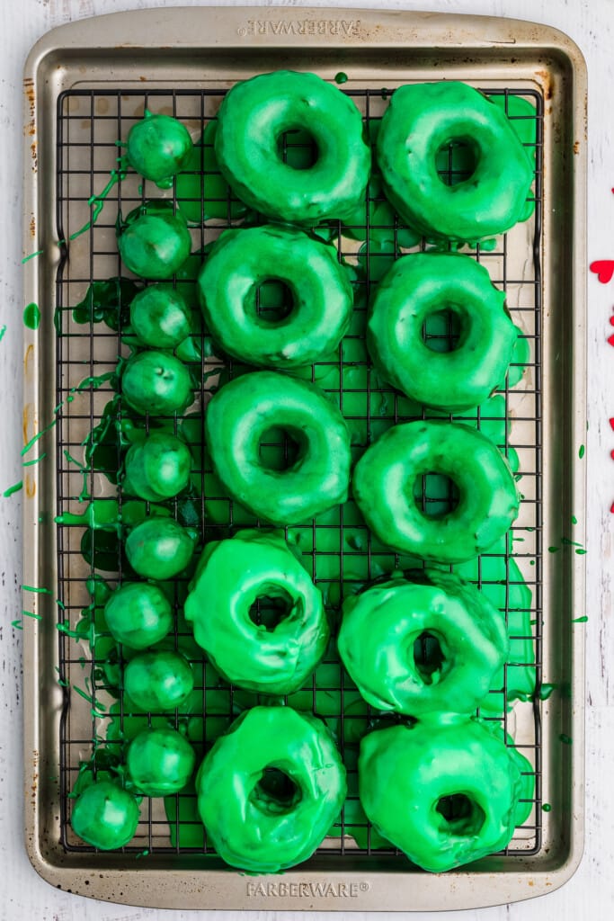 Overhead image of donuts with green frosting on cooling rack