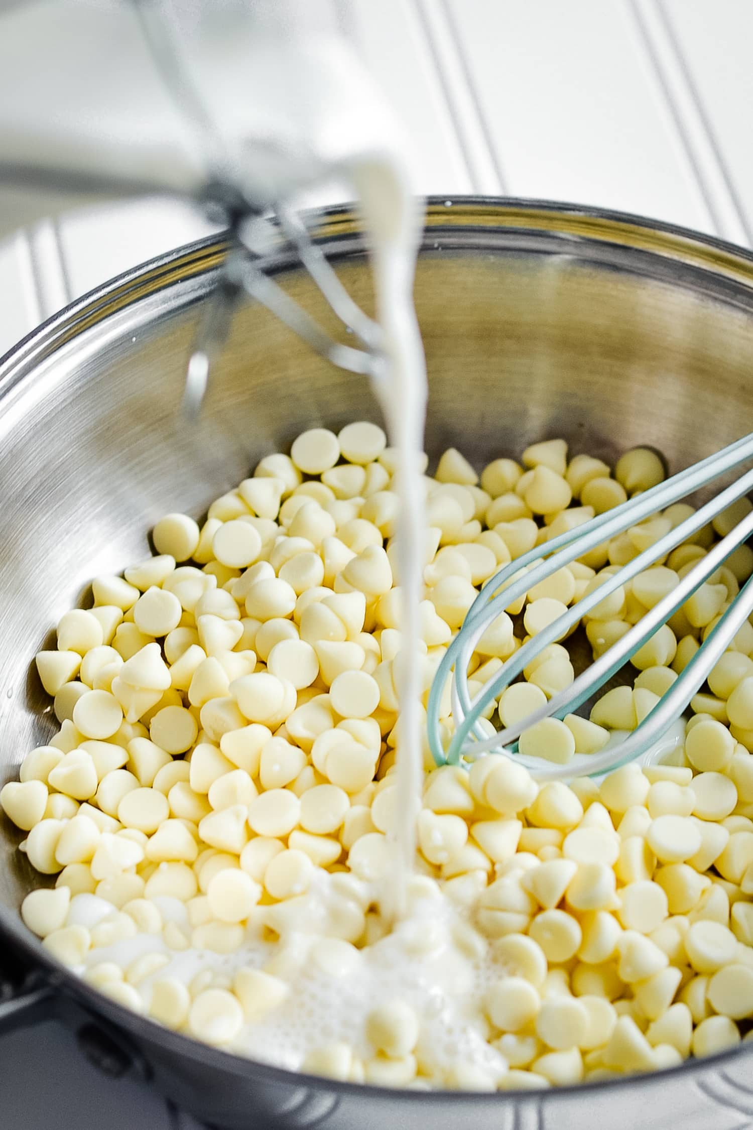 Pouring milk into saucepan with white chocolate chips