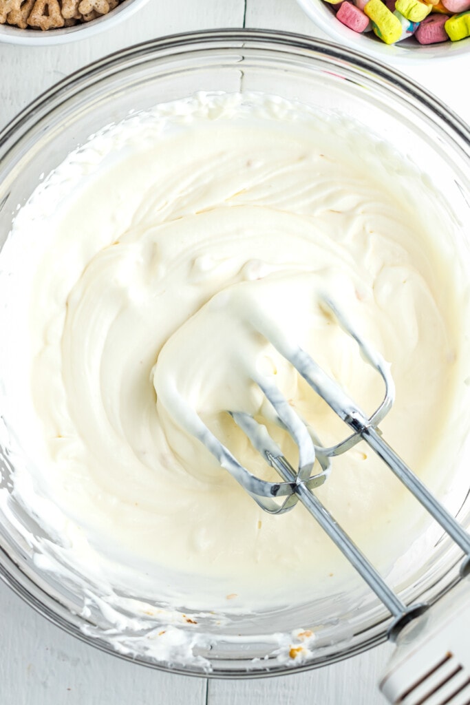 Glass mixing bowl with whipped cream and egg beaters in it