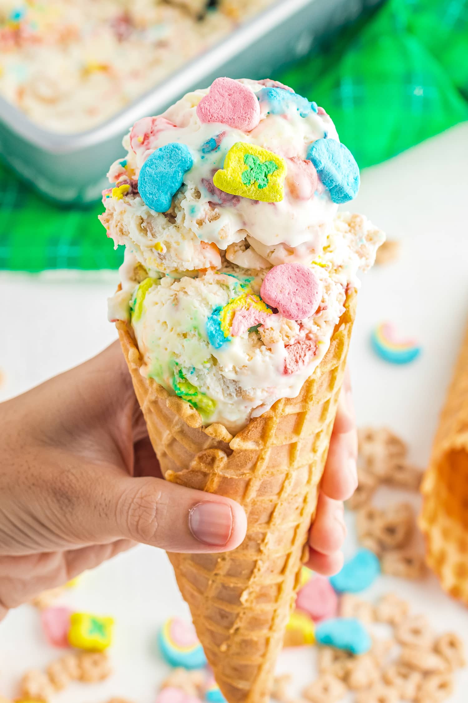Hand holding a cone with lucky charms ice cream