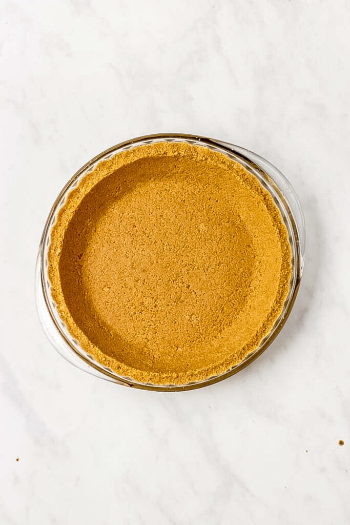 Crushed Golden Oreos with butter in pie plate pressed into crust form