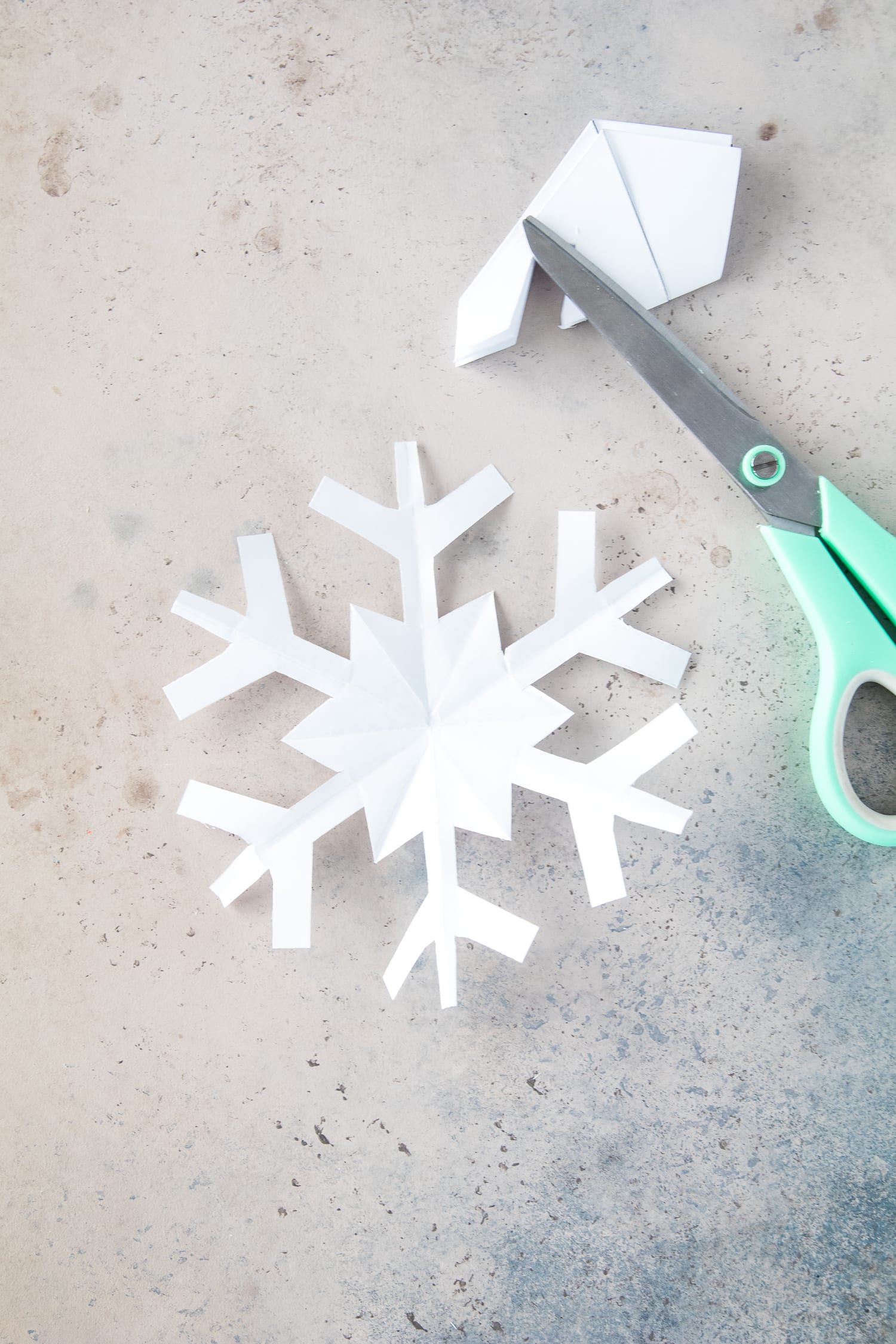 Paper snowflake and scissors laying on board