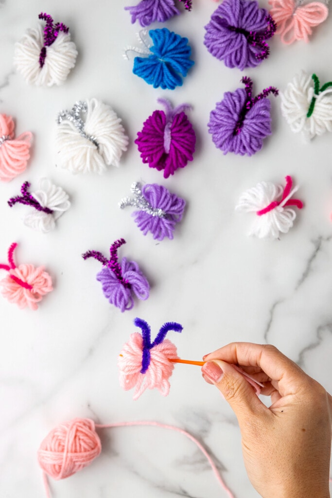 Threading a plastic knitting needle through yarn butterfly