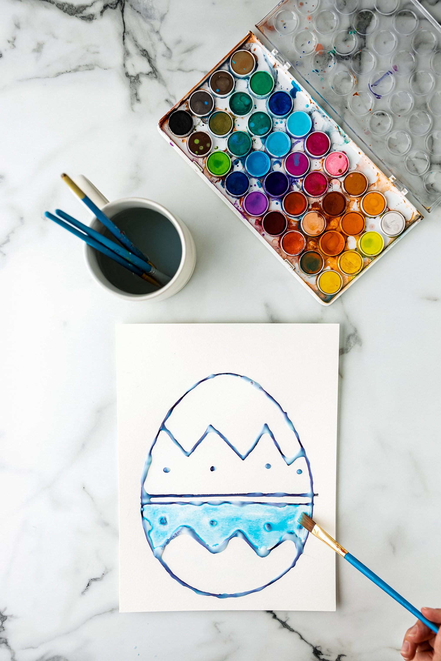 Painting an Easter Egg outline with water colors on white paper