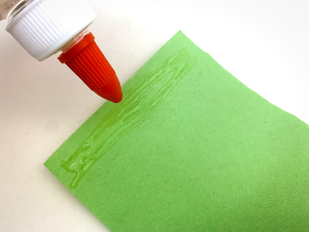 Lining edge of green construction paper with glue