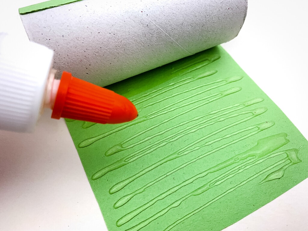 Putting glue on green construction paper
