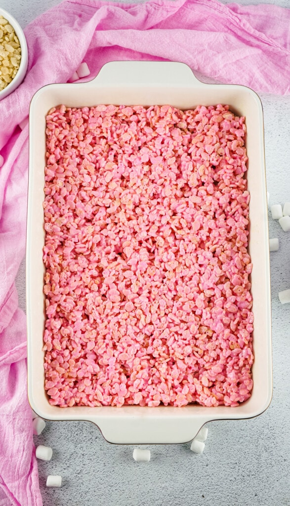White casserole dish with a layer of pink rice krispies treats