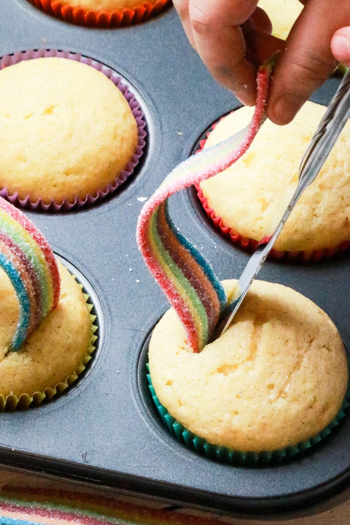 Placing a rainbow candy on top of a vanilla cupcake