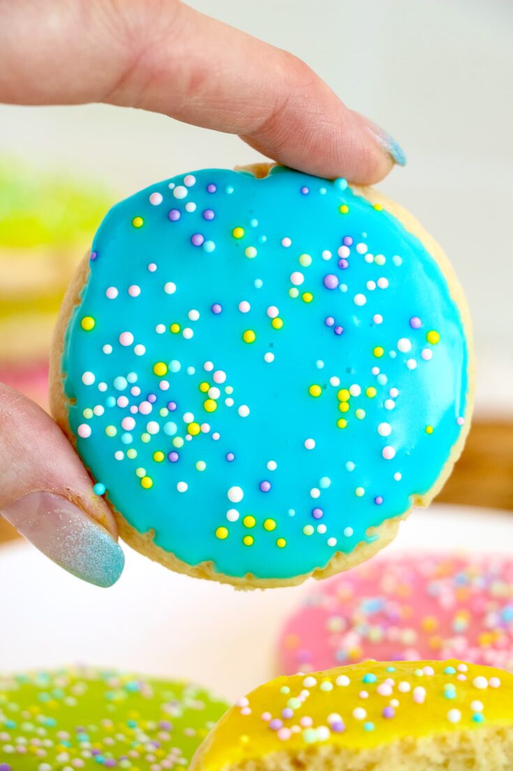 Hand holding a blue frosted sugar cookie