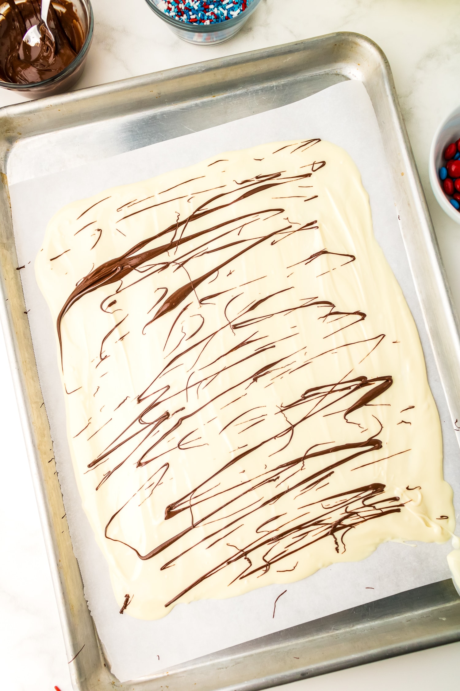 Sheet pan with melted white candy melts drizzled with chocolate