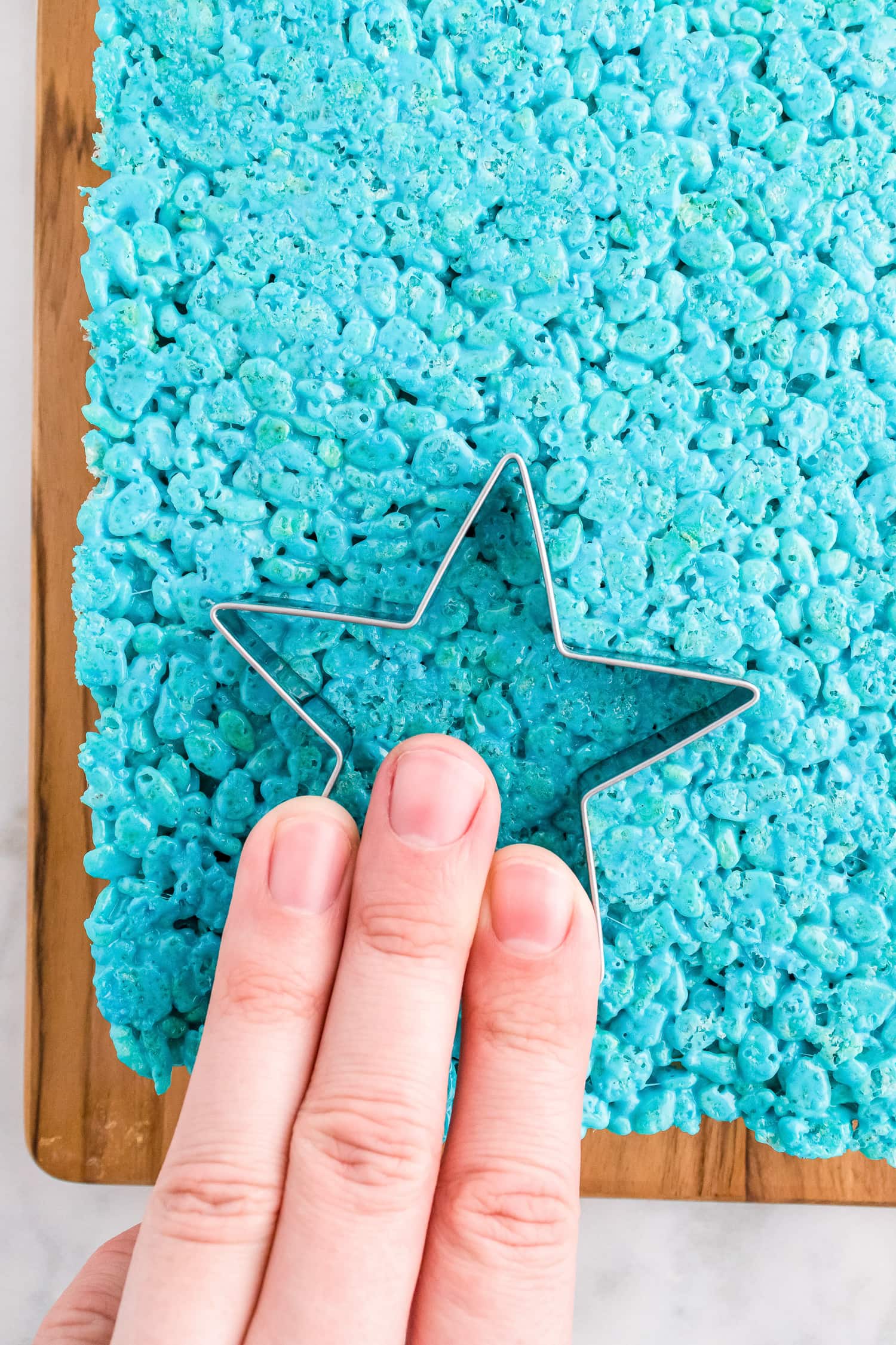 Hand cutting out rice krispie treats with star cookie cutter