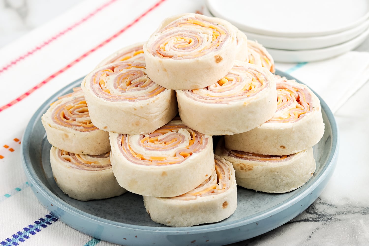 Ham and cheese roll up sliced and stacked on plate