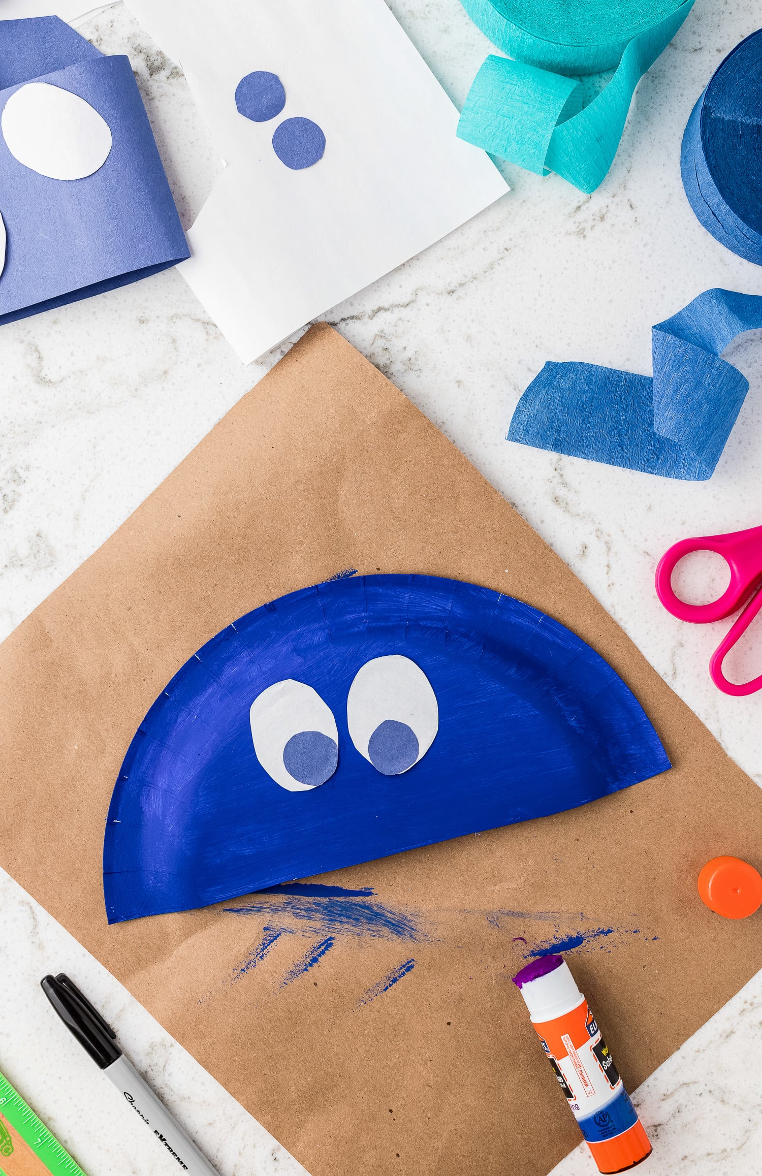 Gluing blue paper circles on white for eyes