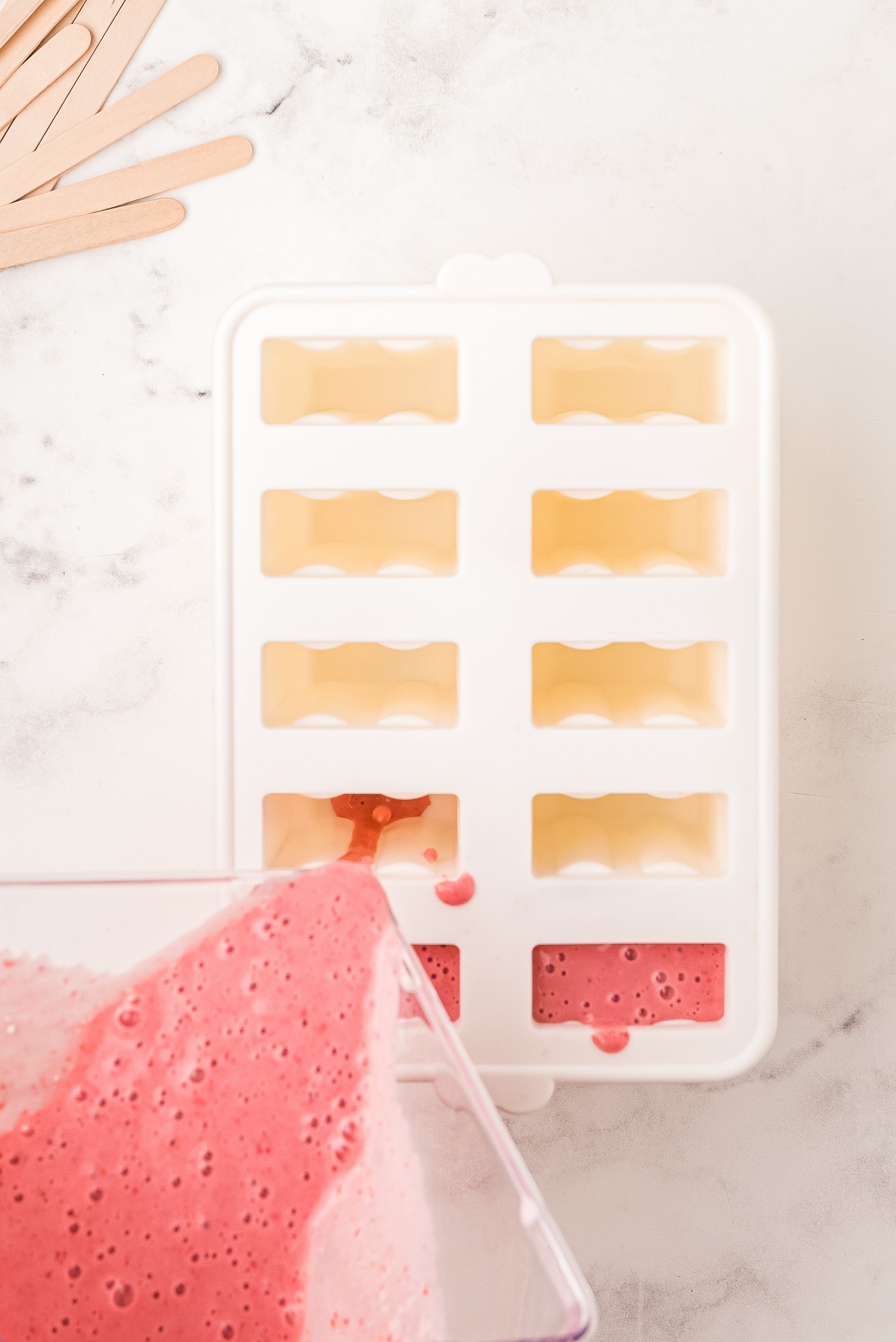 Pouring strawberry banana yogurt mixture into popsicle molds