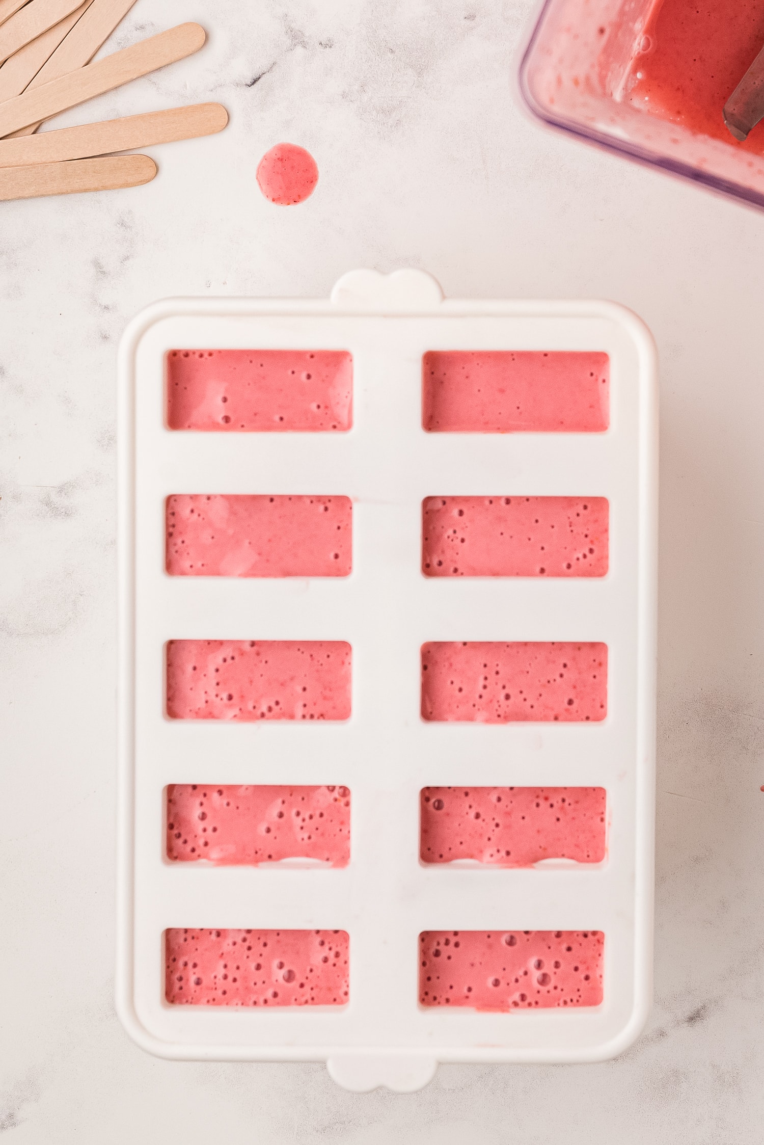 Popsicle molds with strawberry banana yogurt in them