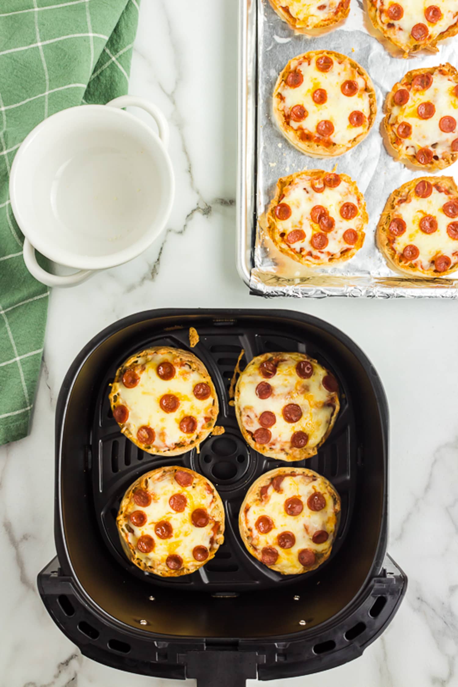 Air Fryer Basket with cooked english muffin pizzas