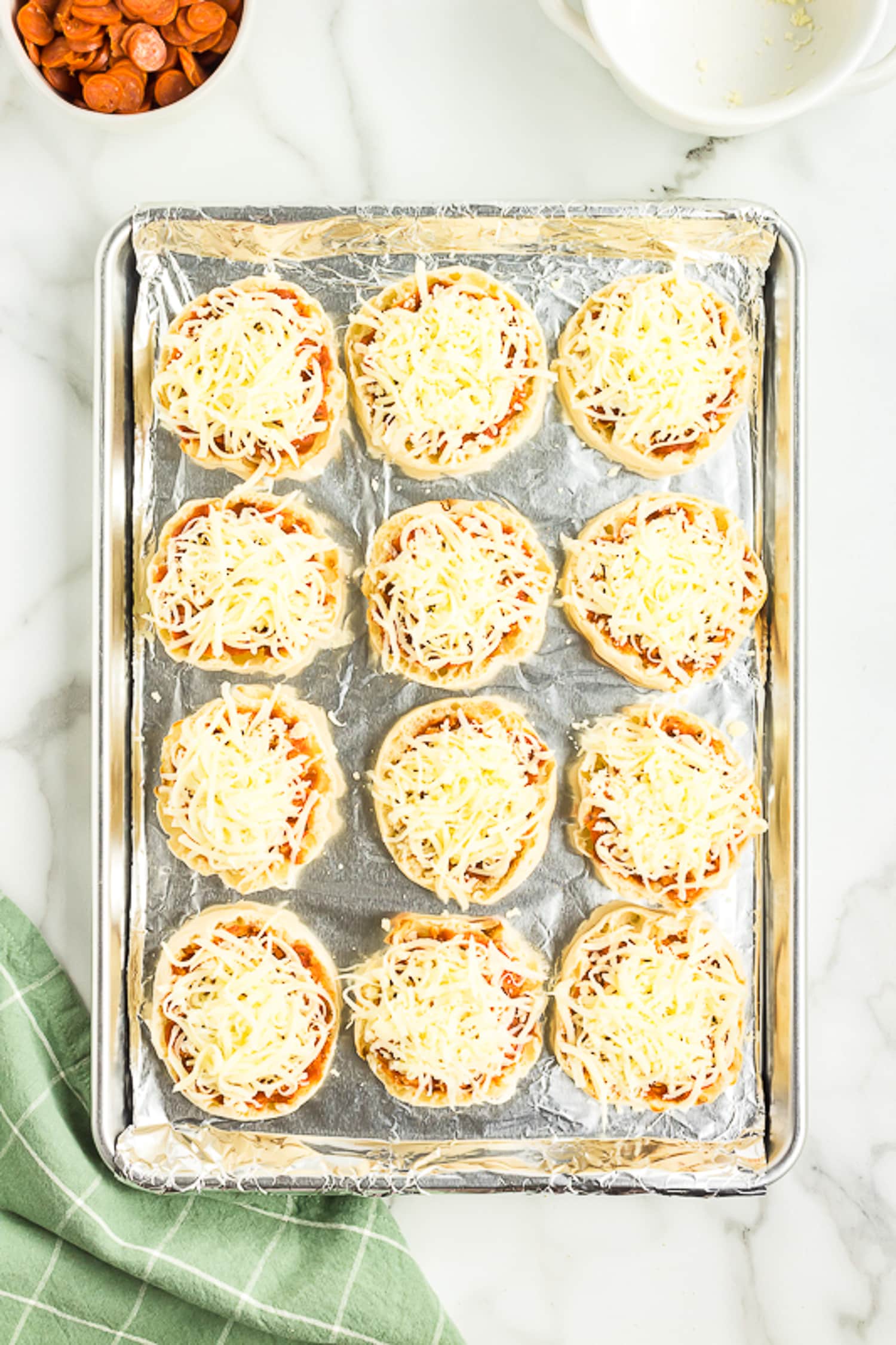 Sheet pan with English muffins topped with Mozzarella cheese