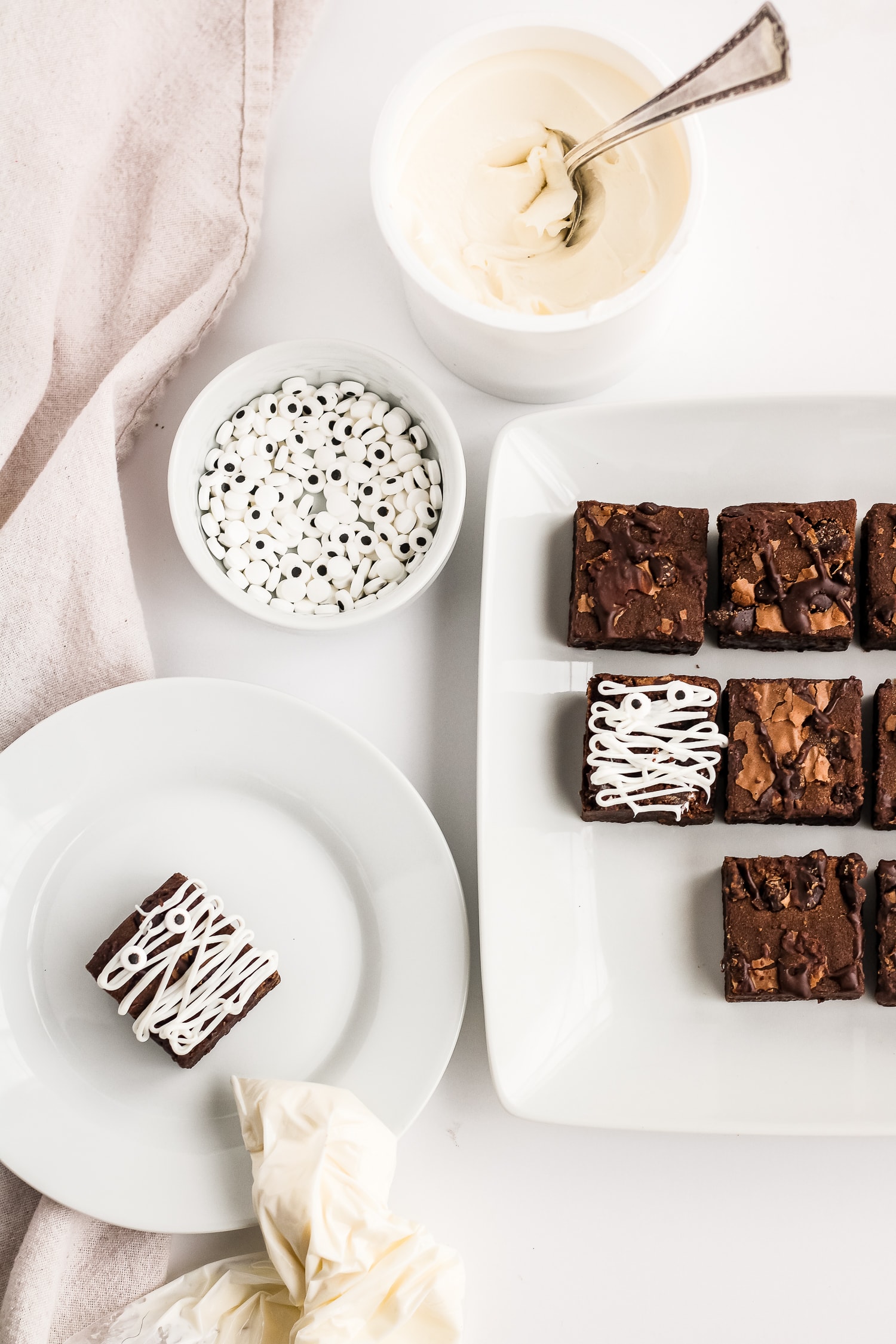 Brownies on white plate drizzled with cake frosting