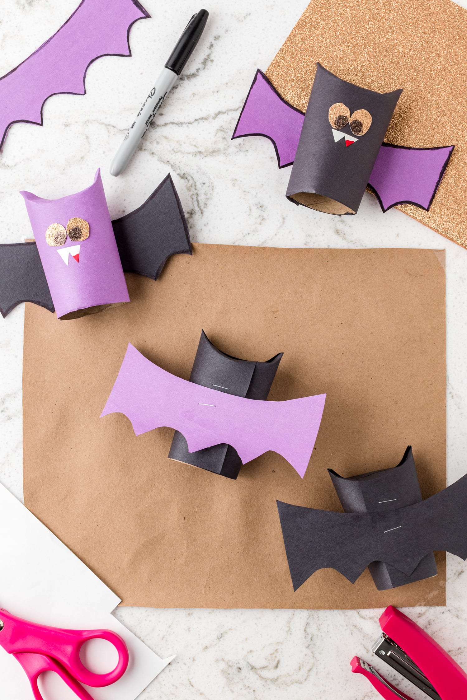 Gluing bat wings on paper towel roll bats