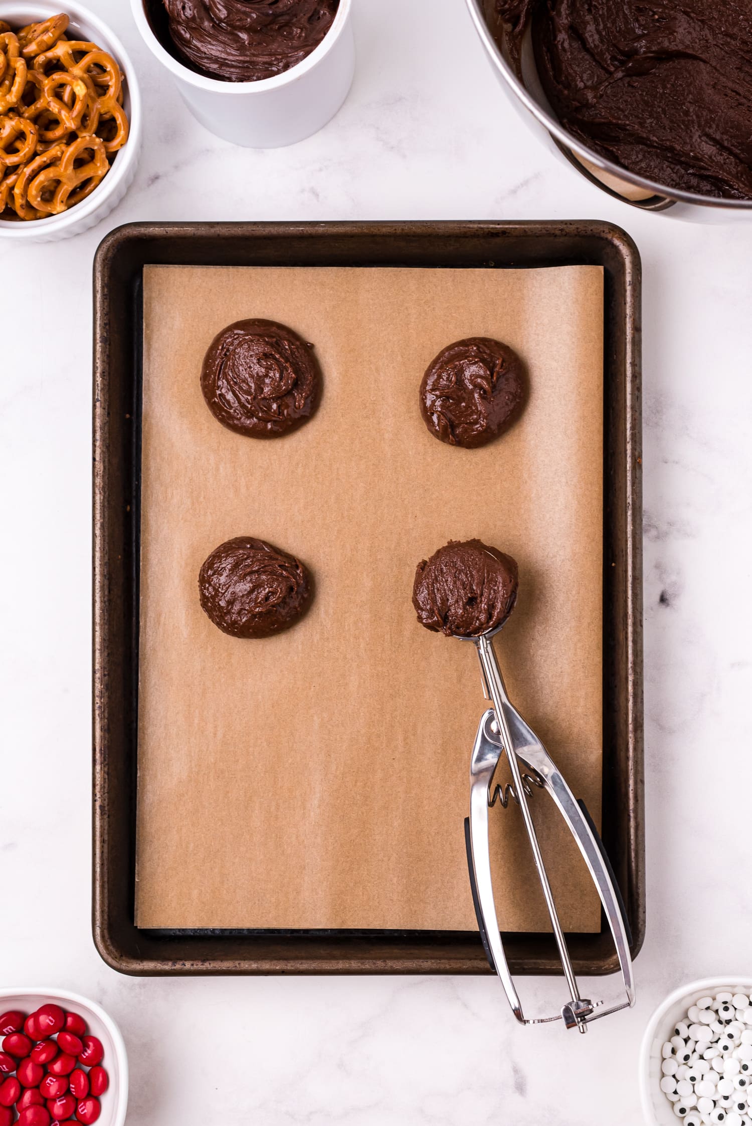 Cookie scoop putting chocolate cookie batter on baking sheet