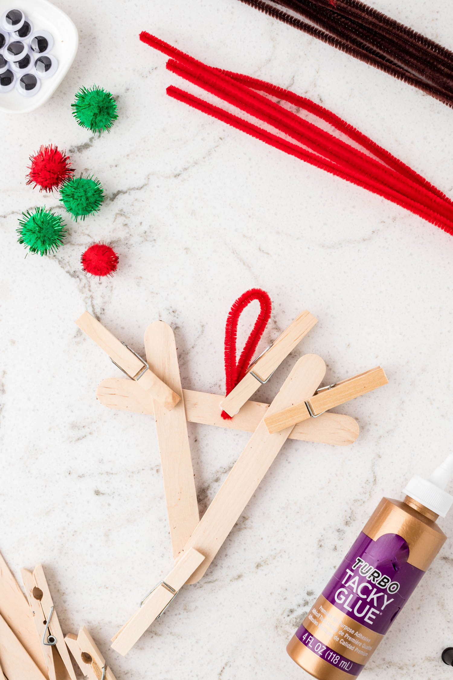 Putting red pipe cleaner on back of reindeer ornament