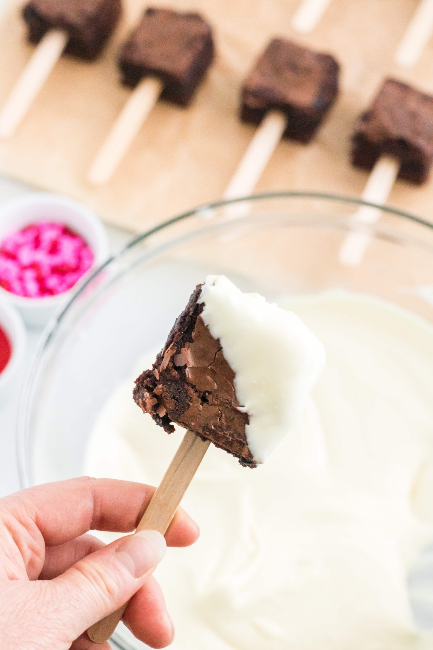 Insert a Popsicle Stick in One end of a Square Brownie and Dip into the Melted White Chocolates