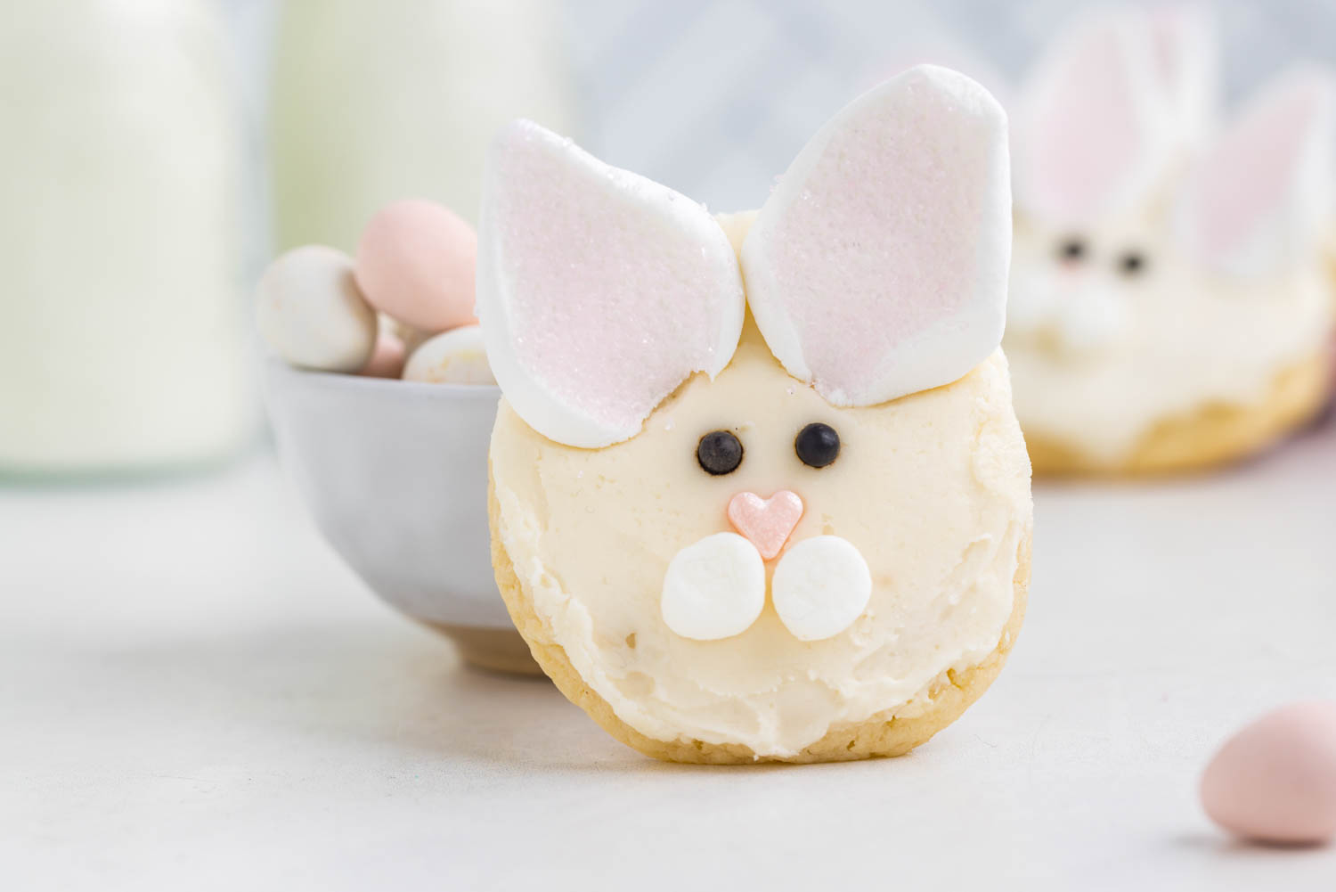 a Bunny Face Cookie Leaning against a Bowl of Candy Eggs
