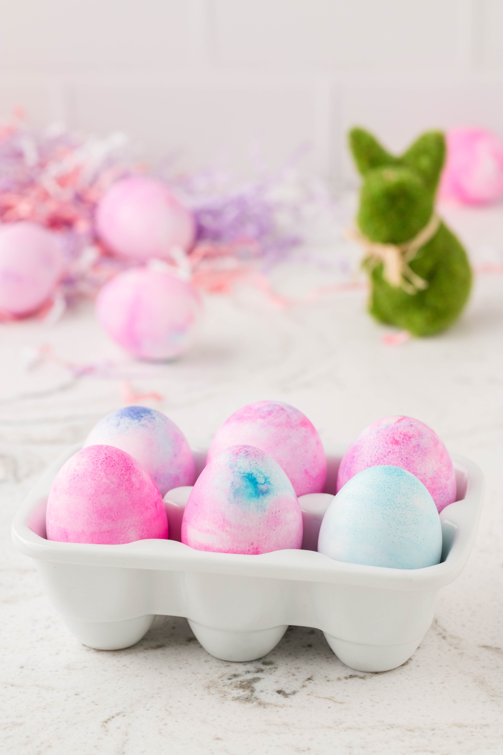 Easter Eggs Displayed in an Egg Carton with a Bunny in the Background