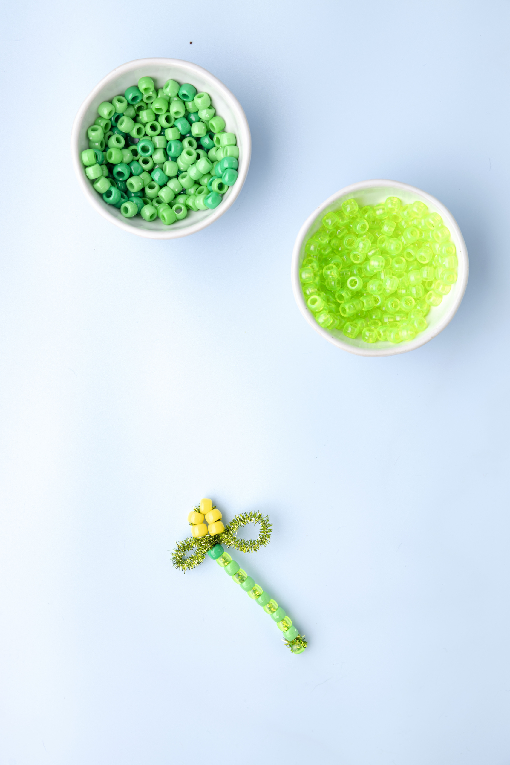 Place five yellow pony beads onto the pip cleaner end and twist the end around the center of the leaves