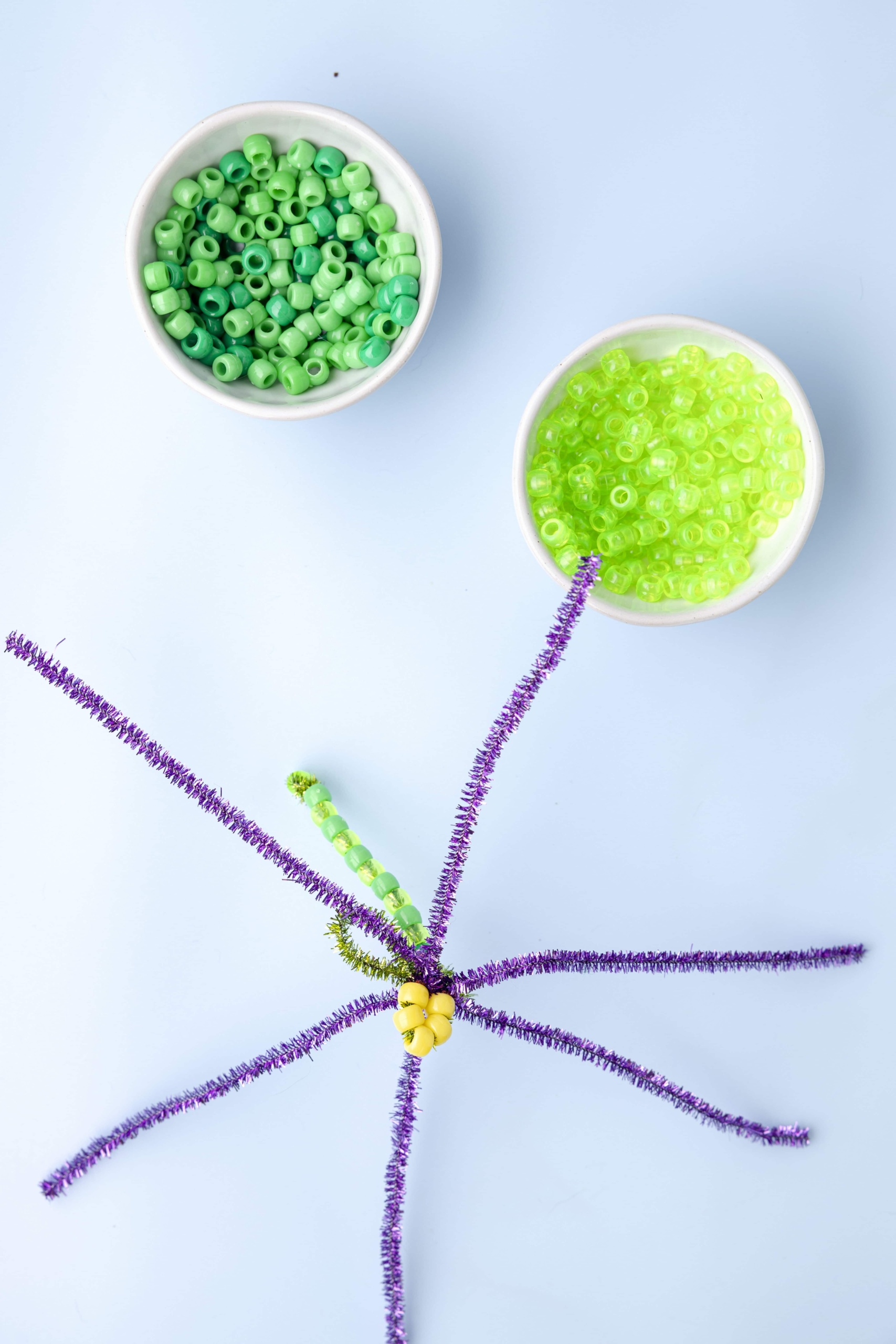 Twist three pipe cleaners on the base of the yellow beads and spread them apart.