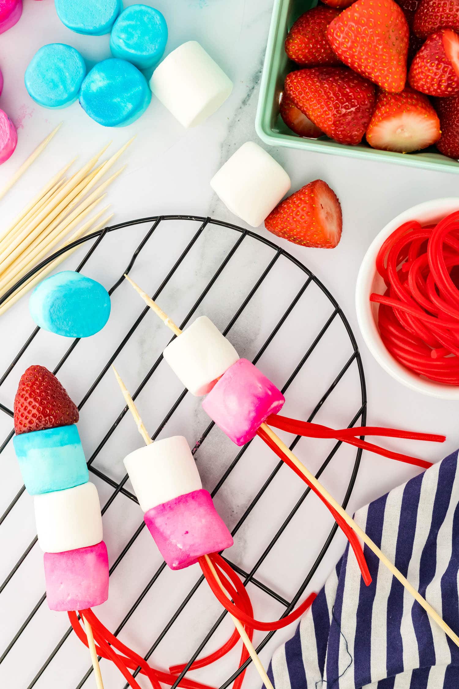 Push a Skewer through the Red Marshmallow and add a White Marshmallow and blue Marshmallow to the top
