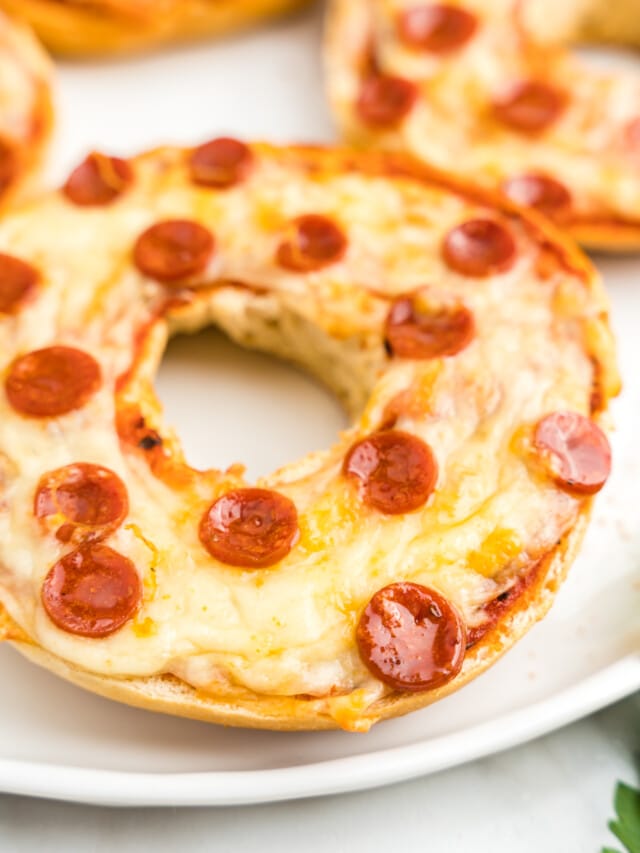Close Up Photo of Cooked Pizza Bagels Displayed on a White Plate.