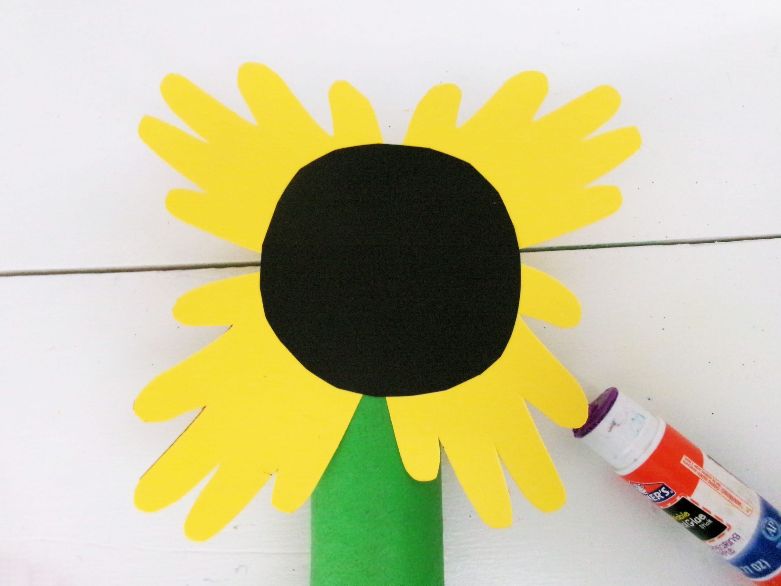 Sunflower hands glued to the green paper towel roll.
