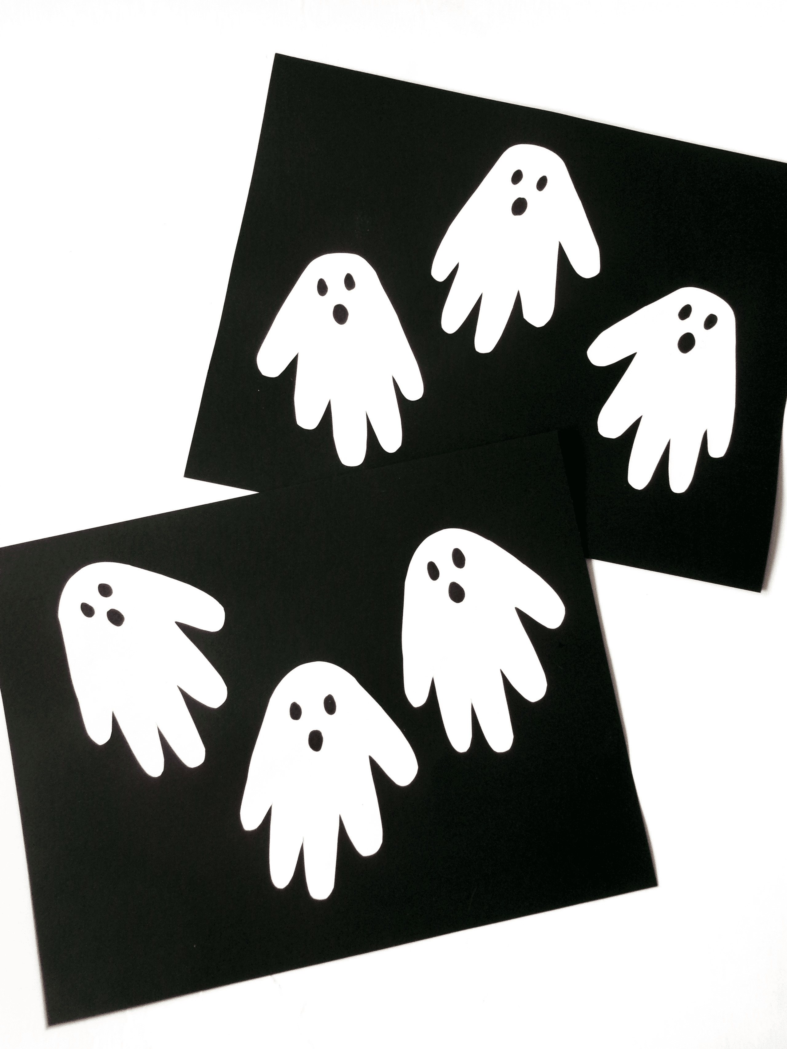 two black sheets with three ghost handprints on each.